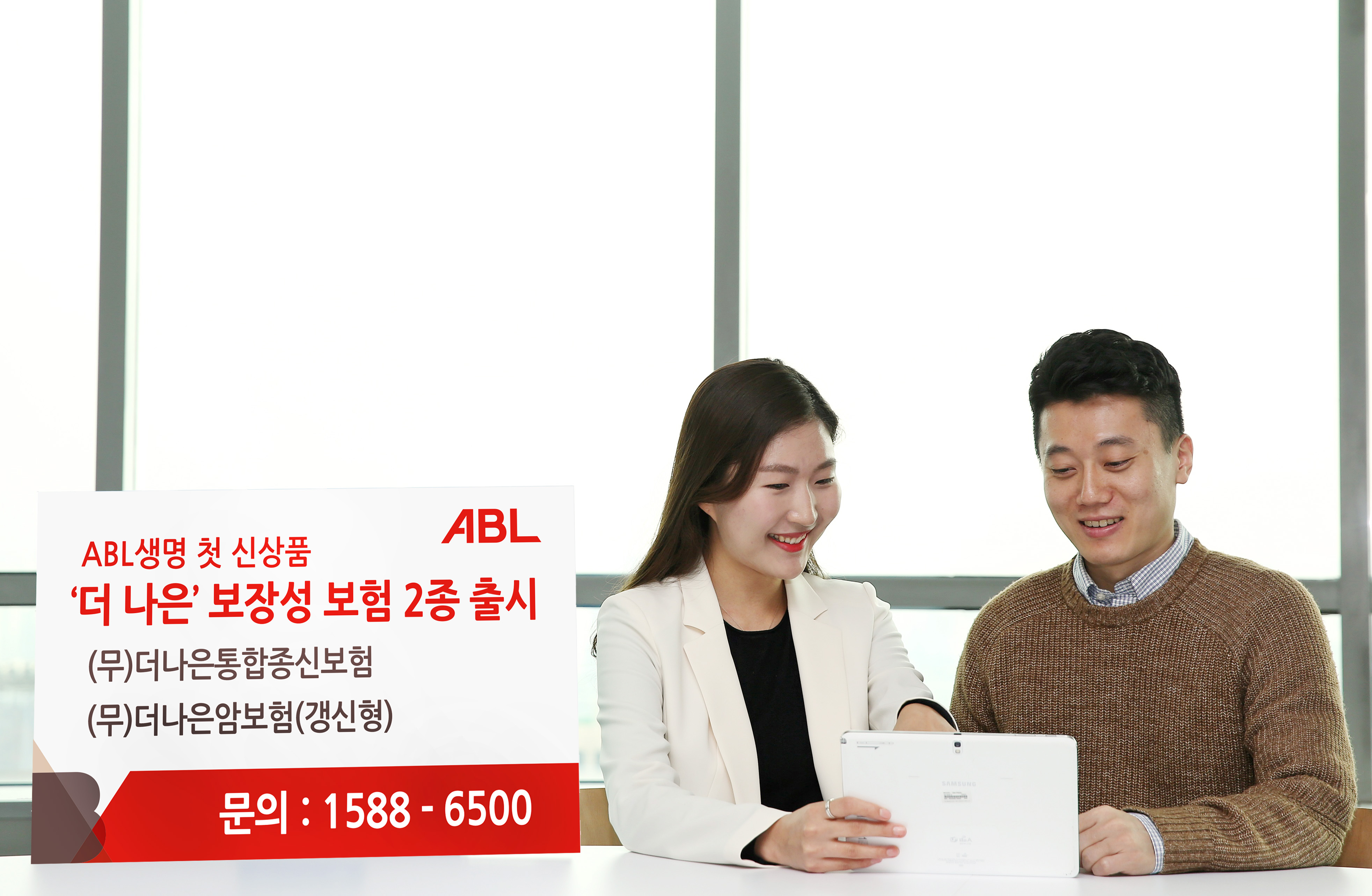 ABL생명 첫 신상품 더나은 보장성 보험 2종 출시, (무)더나은통합종신보험, (무)더나은암보험(갱신형), 문의 : 1588-6500, 여성상담사가 밝게 웃으며 태블릿 PC로 신상품을 남성고객에게 설명하고 있는 모습의 사진